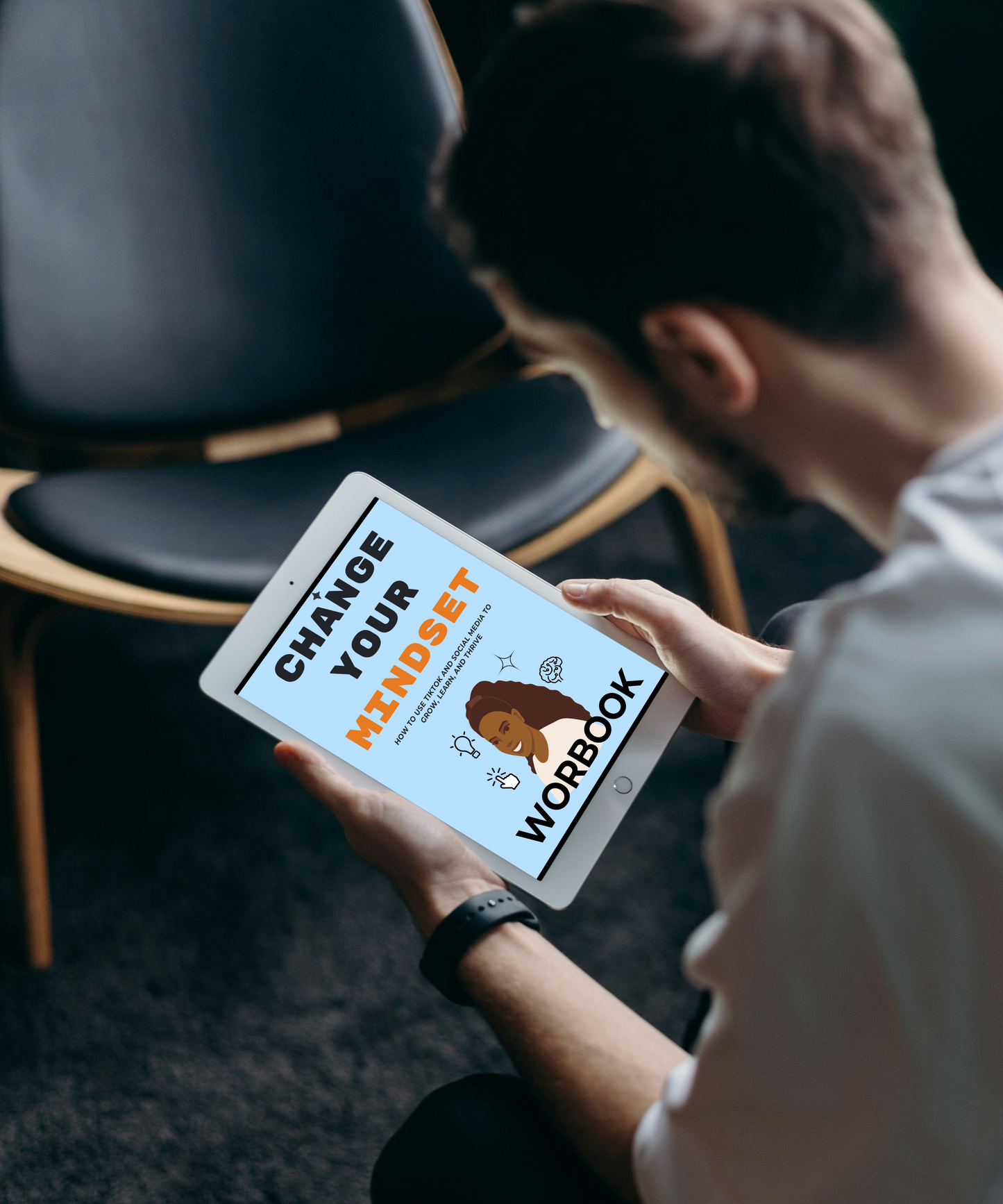 Person holding a tablet with 'Change Your Mindset Workbook' displayed on the screen.