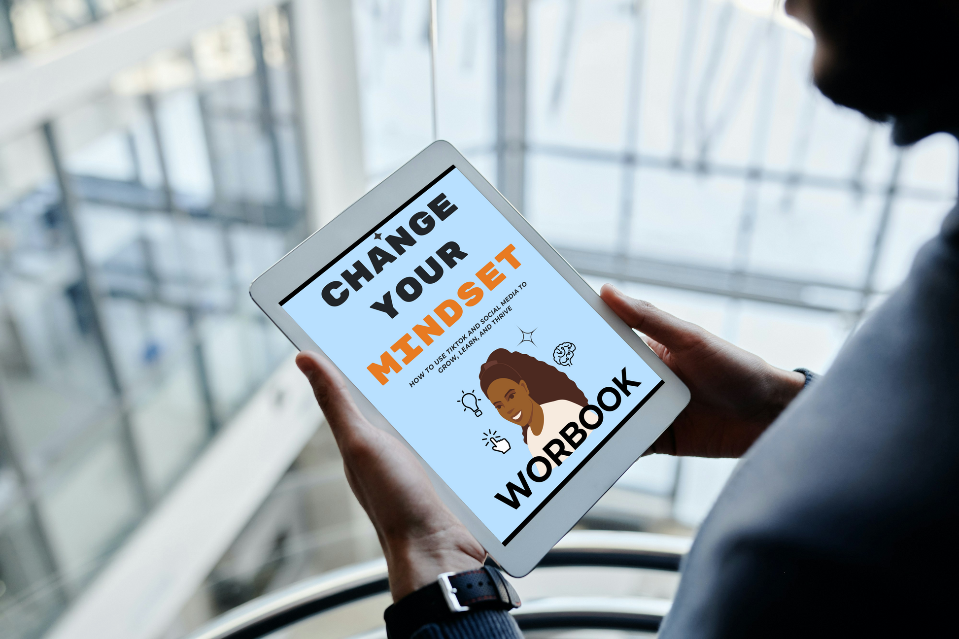 Person holding a tablet with 'Change Your Mindset Workbook' on the screen