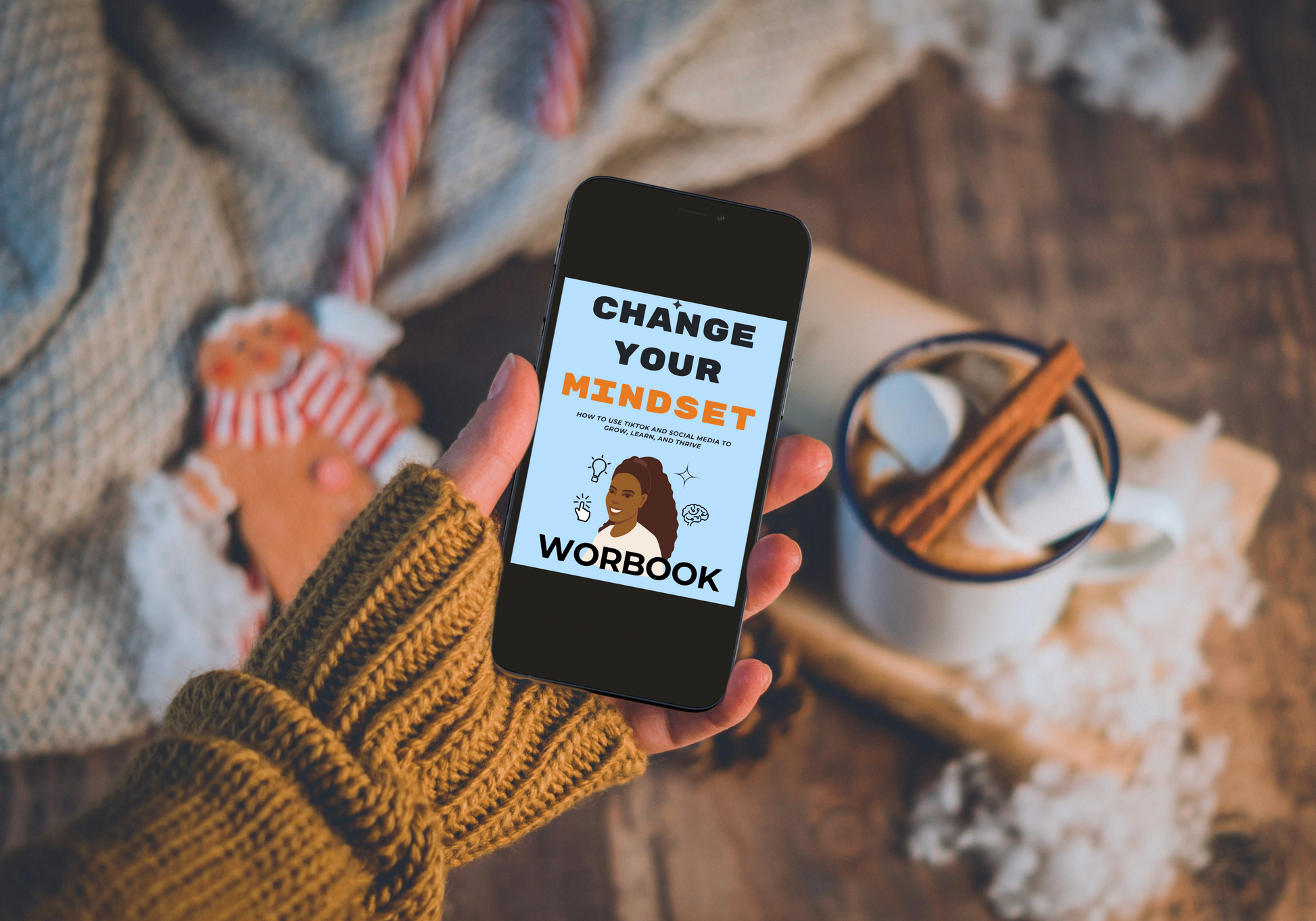 Hand holding a phone with 'Change Your Mindset Workbook' app on a cozy background