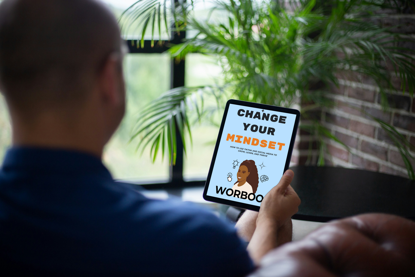 Person holding a tablet with 'Change Your Mindset' app on a blurred indoor background
